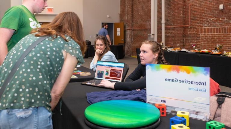 Members of the public interact with UNE students at a table